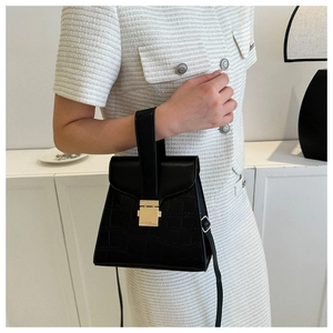Détail du sac à main noir à motif crocodile avec boucle dorée et bandoulière réglable