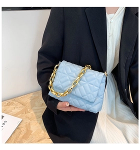 Close-up of quilted light blue shoulder bag with chunky gold chain handle detail