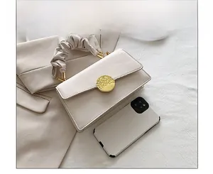 Vue détaillée du sac bandoulière crème avec poignée à volants et boucle dorée