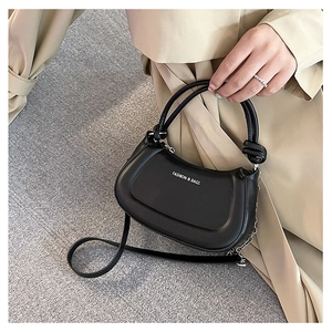 Detail of black faux leather handbag with circular dual handles and silver chain link