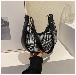 Close-up of black crescent underarm bag with silver rhinestone studs and leather strap