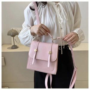 Close-up detail of a minimalist pale pink PU leather square bag with golden metal buckles