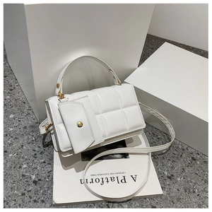 Detail of white quilted rectangular handbag with detachable mini pouch and gold hardware