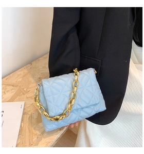 Detail of light blue quilted PU leather bag featuring a chunky gold acrylic chain strap