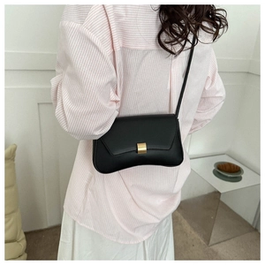 Minimalist black crescent crossbody bag with gold buckle shown in a lifestyle setting
