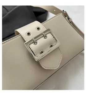 Detail of beige shoulder bag featuring a silver metal square buckle and leather strap