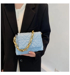 Detail of light blue quilted shoulder bag featuring gold chain and chic faux leather texture