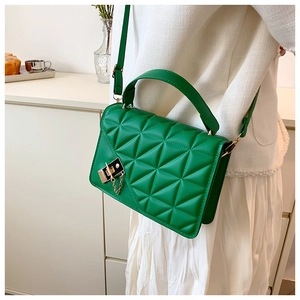 Close-up of bright green quilted crossbody bag featuring metal lock and gold chain details