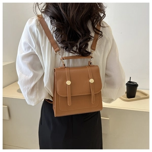 Brown vintage faux leather backpack with gold buckle shown on a model in a cafe