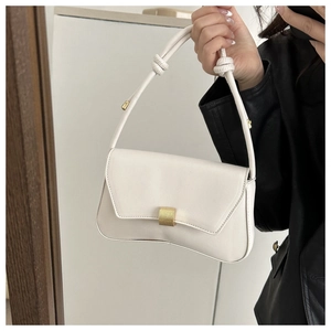 Close-up of minimalist white baguette bag with gold buckle and knotted strap detail
