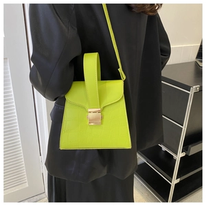 Mannequin portant un sac à main vert fluo motif crocodile avec fermoir doré sur tailleur noir