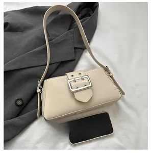 Detailed view of cream faux leather underarm bag with oversized silver buckle and strap