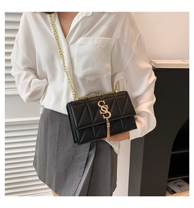Detailed close-up of a black quilted flap bag with gold S-buckle and chain strap