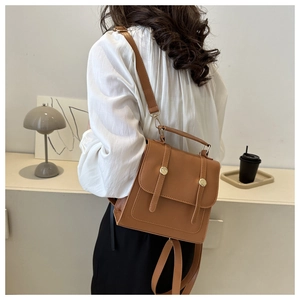 Close-up of caramel brown leather backpack with gold metal buckles and messenger style flap
