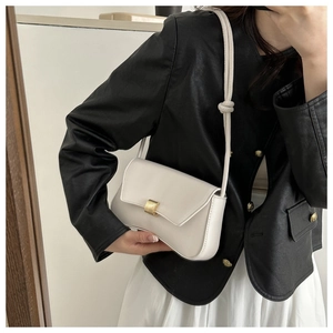Detail of white leather crossbody bag featuring gold buckle and knot strap design