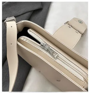Detail of silver metal zipper and premium leather texture on beige underarm bag