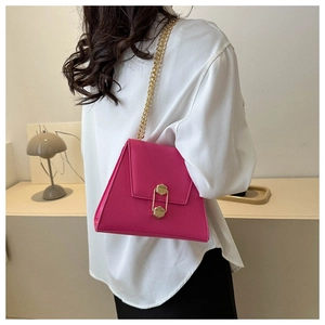 Detail of fuchsia trapezoid bag with gold chain strap and geometric metal buckle