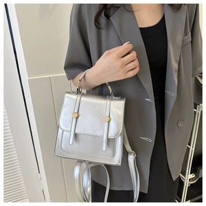 Detail view of silver metallic backpack with golden buckle on a grey blazer outfit