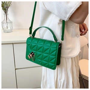 Detail of vibrant green quilted handbag with geometric pattern and gold chain link