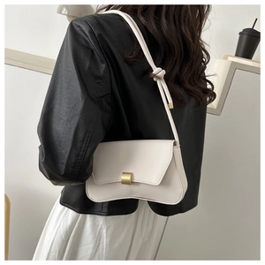 Detail of minimalist beige shoulder bag showing gold square buckle and leather texture