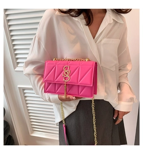 Detail of bright pink quilted crossbody bag with gold SS logo and tassel fringe