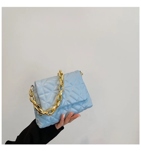 Close-up of light blue quilted PU leather shoulder bag with thick gold chain handle