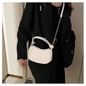 Detail of white half-moon saddle bag with knot handle and chain strap on black blazer