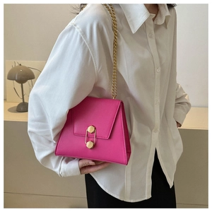 Detailed view of magenta trapezoid handbag with gold chain and unique hexagonal lock