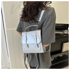 Detail of silver metallic PU mini backpack with flap closure and decorative buckles