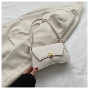 Detail of a beige baguette bag with a gold square buckle on a soft blazer