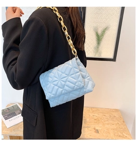 Detail of light blue quilted PU shoulder bag featuring a chunky gold acrylic chain strap