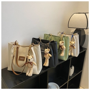 Detail view of large tote bags in four colors with teddy bear charms and gold chain handles