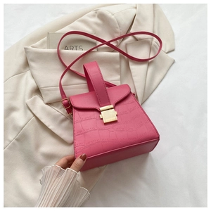 Sac à main rose à motif crocodile sur blazer beige avec boucle dorée et bandoulière