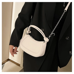 Detail of cream half-moon crossbody bag with knot handle and silver chain strap