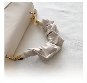 Close-up of cream leather handbag with stylish scrunchie handle and gold metal rings