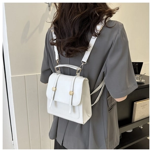 Close-up of white minimalist backpack being worn by a model in a modern interior setting