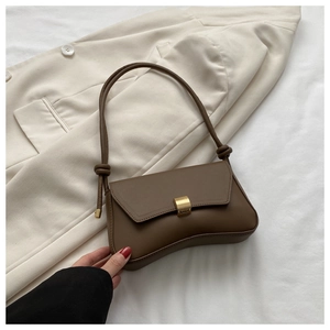 Detail of coffee brown baguette bag with golden buckle on white blazer