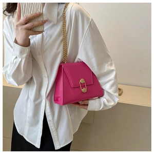 Model wearing a rose pink square crossbody bag with gold hexagonal lock and chain strap