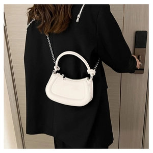Woman in black blazer wearing a white leather half-moon bag with silver chain strap
