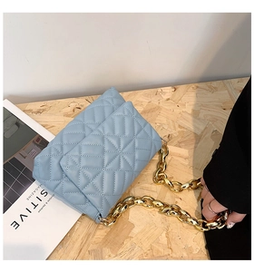 Detail view of light blue quilted leather handbag with chunky gold chain strap and stitching