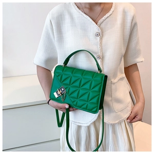 Detail of green quilted handbag with golden chain strap and triangle texture