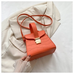Gros plan du sac à main orange vif à motif crocodile avec boucle en métal doré élégante