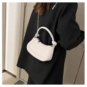 Close-up of white half-moon leather bag with silver chain and circular handle detail