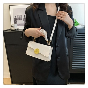 Detail of minimalist beige leather crossbody bag with gold buckle and ruched handle