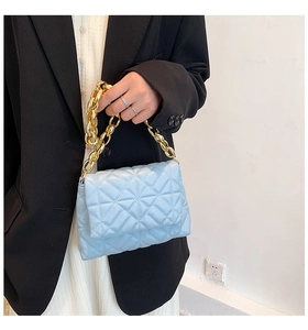 Close-up of light blue quilted PU leather bag with bold gold acrylic chain detail
