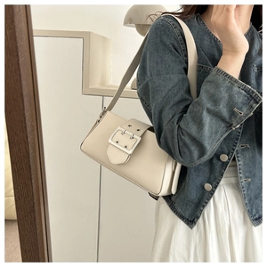 Detail of cream leather shoulder bag with large silver metal buckle and pebble texture