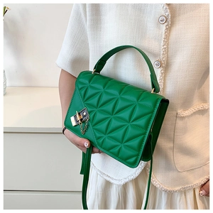 Macro shot of green quilted faux leather texture with elegant gold hardware and chain detail