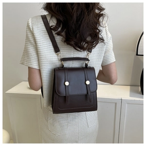 Rear view of a model wearing the dark brown vintage backpack with gold metal buckles