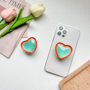 Dual red and green gradient heart-shaped collapsible phone socket on a white smartphone