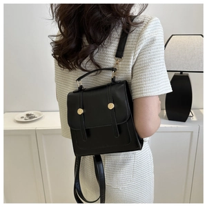 Rear view of a model wearing a black vintage leather backpack with gold hardware details